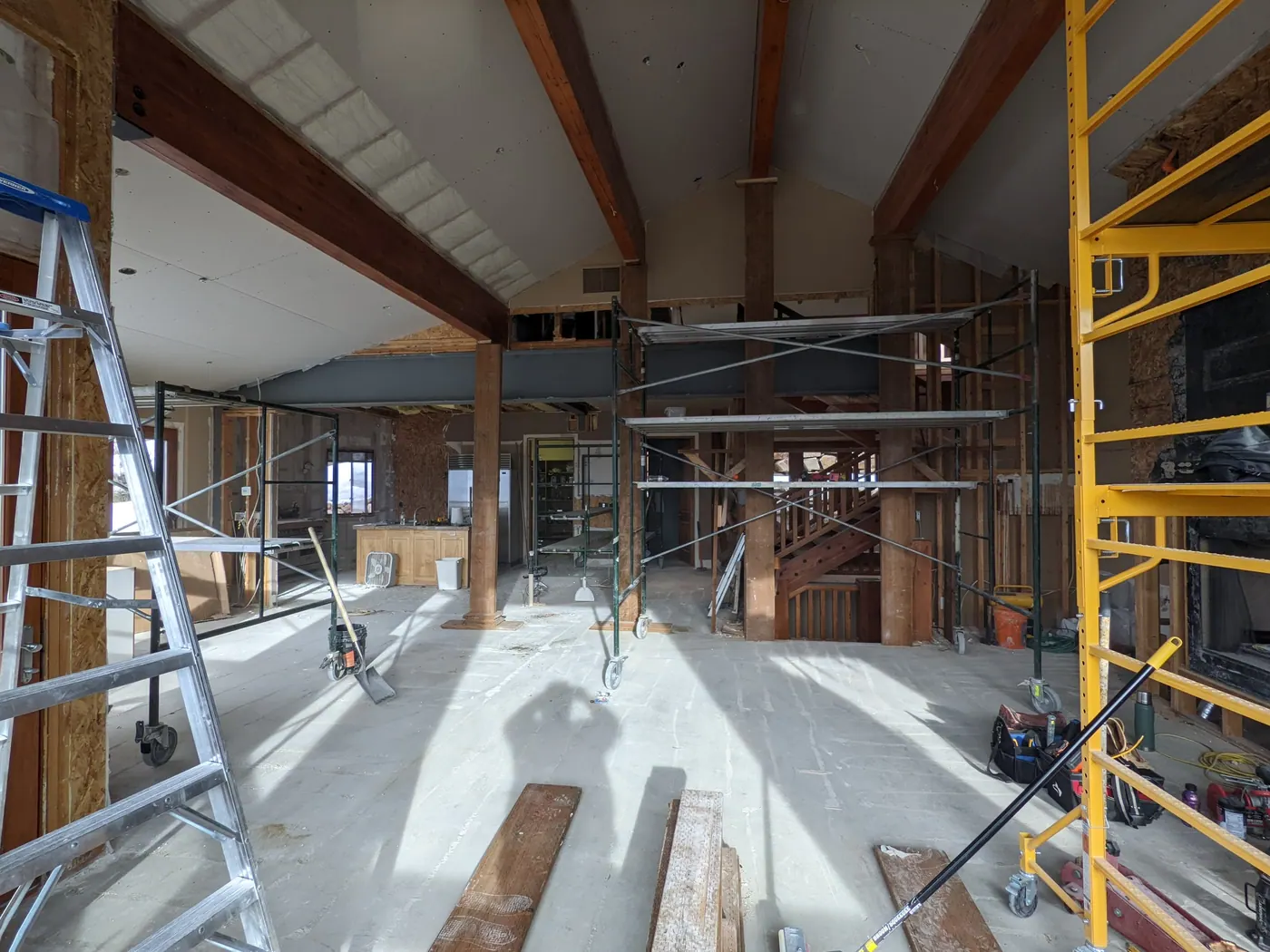 Beam in, bearing walls out — Mid-construction: the new steel beam is set and shored while the walls that were carrying the roof come out beneath it