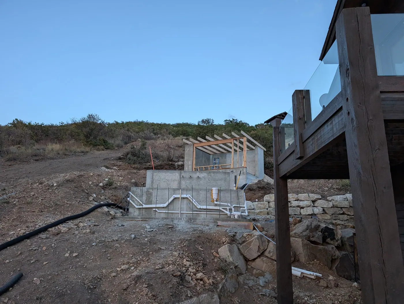 Stepped foundation on a hillside lot — Concrete walls stepping down a slope with dowels in place for the next pour — routine on the benches, and unforgiving if the steps are wrong