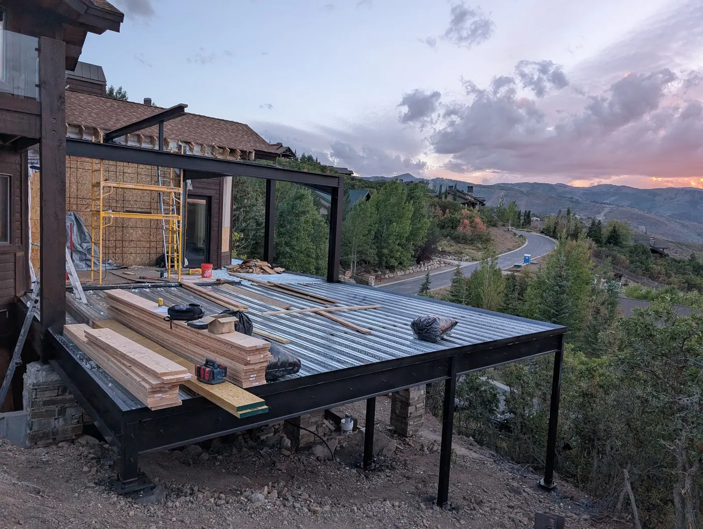 Steel-framed deck over a slope — An elevated deck framed in steel and carried on columns down the hillside — the condition where prescriptive deck details stop being usable