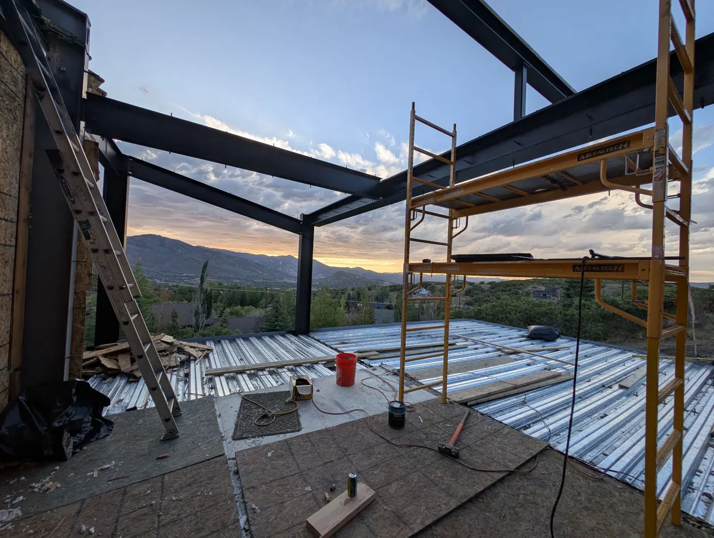 Steel framing at dusk — Structural steel and deck framing on a hillside addition